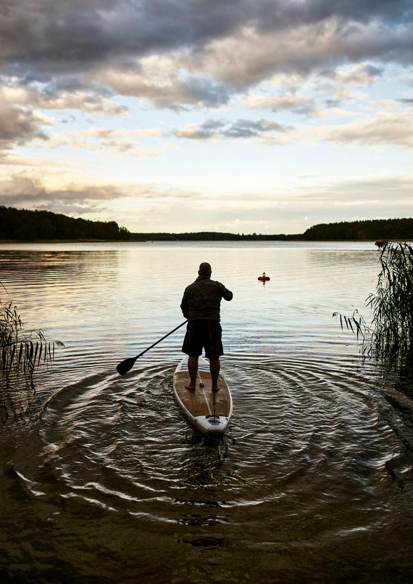 Ein Mann steht auf einem SUP auf einem See