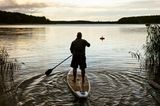 Ein Mann steht auf einem SUP auf einem See