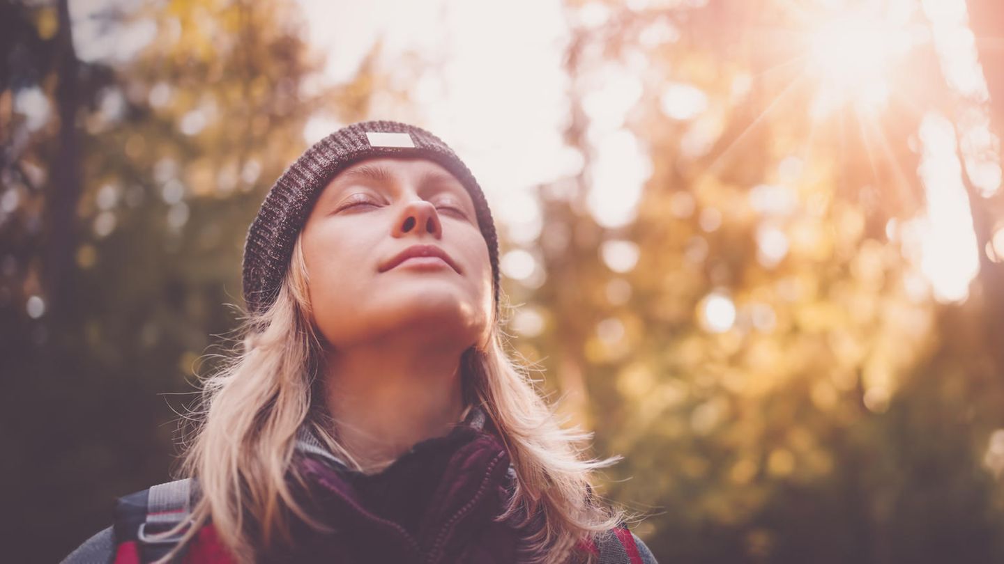 Eine Frau im Wald, die entspannt die Augen schließt
