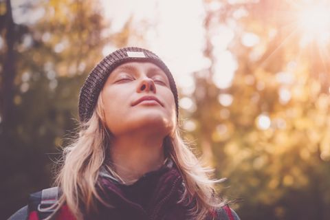 Eine Frau im Wald, die entspannt die Augen schließt