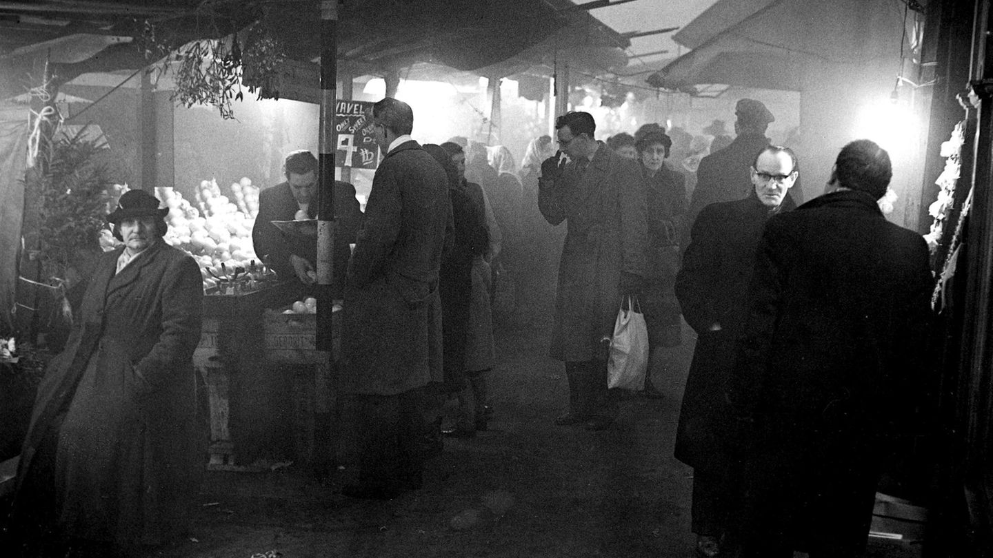 Markttreiben im Dunkeln Schwarz-weiß-Foto von Passanten, die im Smog auf einem Markt einkaufen