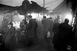 Schwarz-weiß-Foto von Passanten, die im Smog auf einem Markt einkaufen