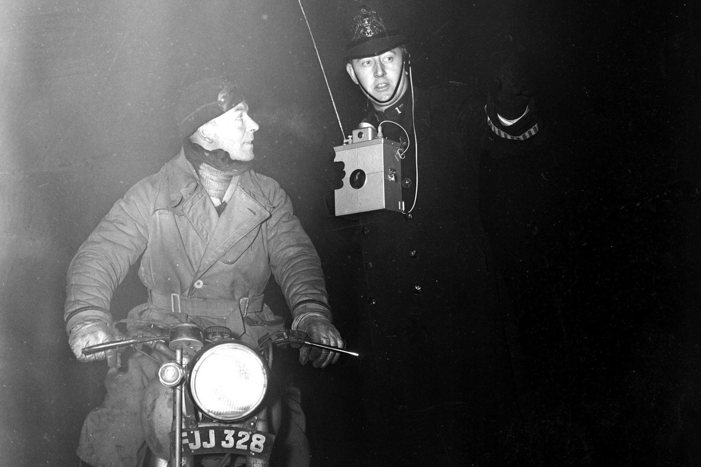 Verloren in der Dunkelheit Schwarz-weiß-Foto eines Polizisten, der einem Motorradfahrer durch den Smog hilft