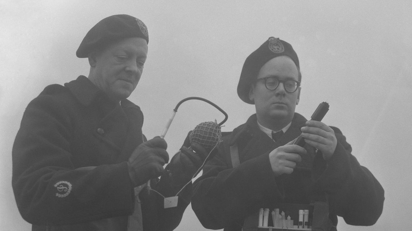 Schwarz-weiß-Foto von zwei Männern, die die Luftverschmutzung messen
