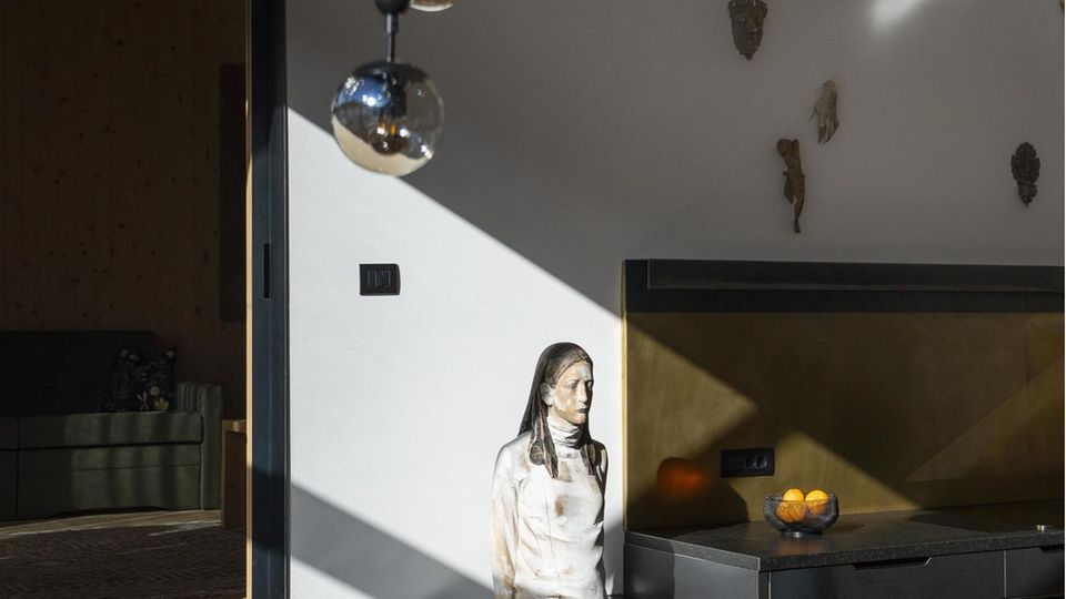 Im Apartment von Artefugium trifft die moderne Kunst von Aron Demetz auf jahrhundertealte Kruzifixe. Als er mit nackten Statuen begann, landeten seine Skulpturen im Fluss. Jetzt ist das Grödner Tal stolz auf seinen berühmten Künstler: "Es hat ein bisschen gedauert"