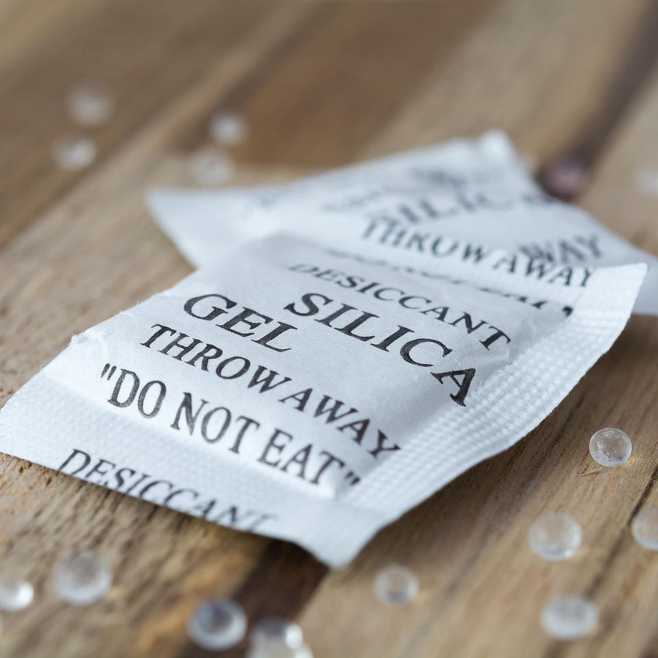 Silica-Gel-Tütchen liegt auf einem Holztisch