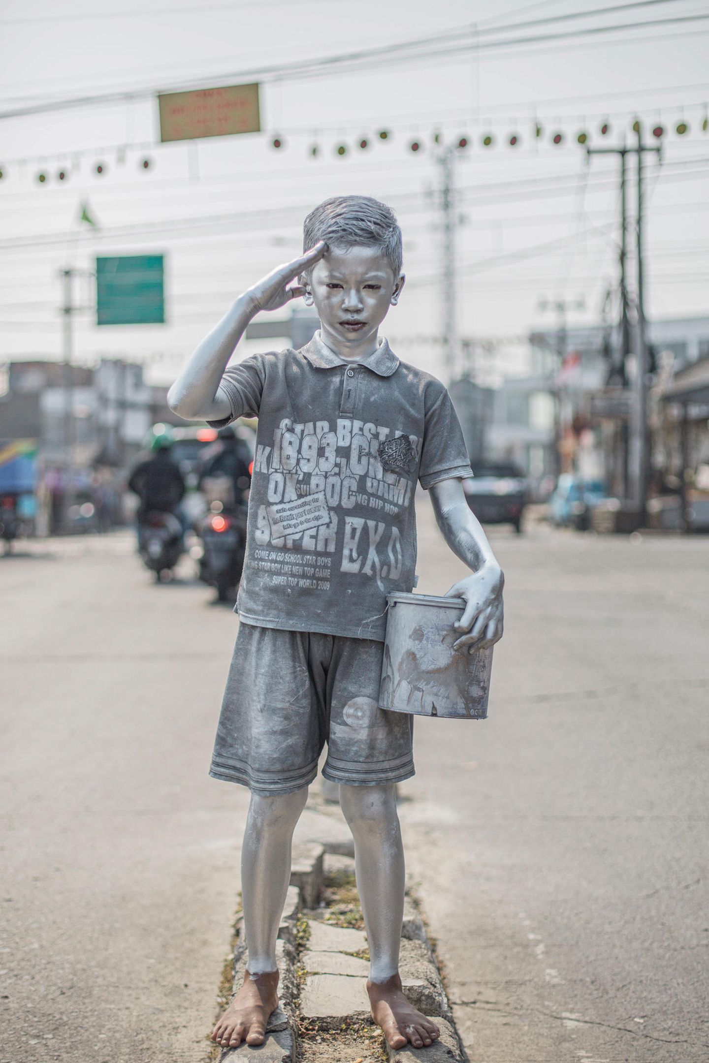 Zwölf Jahre ist Rifki Firmansyah erst alt, muss aber seiner Familie schon helfen, durchs Leben zu kommen. Und so tritt er seit seinem zehnten Lebensjahr in den Straßen der indonesischen Millionenstadt Depok gemeinsam mit anderen Jungen als "silver kid" auf, erbettelt sich so ein paar Rupiah und manchmal auch etwas zu essen, gibt einen Teil des Geldes seinen Eltern ab.  Meist malt sich Rifki um acht Uhr morgens mit Silberfarbe an, um dann bis in den Nachmittag an Verkehrskreuzungen als kleiner menschlicher Roboter aufzutreten. Zur Schule geht er nicht. Der Mix, den die Jungen zum Versilbern ihrer Haut verwenden, reicht von Kerosin bis Blei, enthält Chemikalien und Metalle, die sie sich am Abend mit Seife, Shampoo und groben Waschmitteln von Gesicht und Körper waschen.  Vor einer Zerstörung ihrer Haut aber fürchten sich die „silver kids“ weniger als vor der Polizei, wie sie dem Fotografen Agoes Rudianto erzählten. Auch Rifki ist schon wegen „Störung der öffentlichen Ordnung“ festgenommen worden. Trotzdem sind in den Straßen indonesischer Städte immer mehr Kinder wie Rifki anzutreffen – vor allem seit Beginn der Corona-Pandemie. 