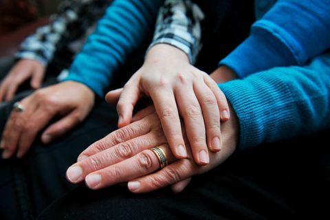 Ein Kind legt die Hand auf die des Vaters, der einen Ehering trägt