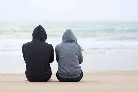 Eine Frau und ein Mann tragen Kaputze und blicken aufs Meer