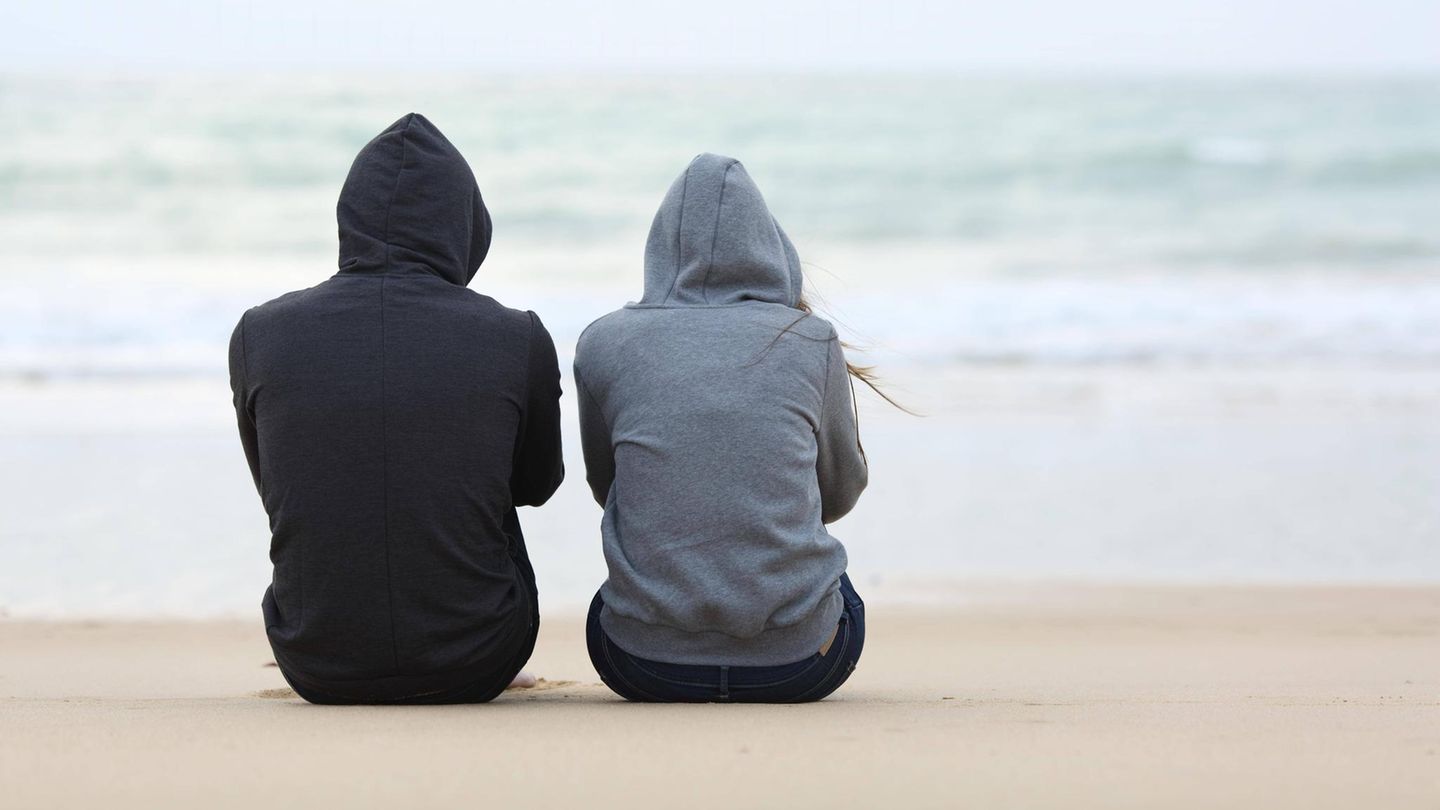 Eine Frau und ein Mann tragen Kaputze und blicken aufs Meer
