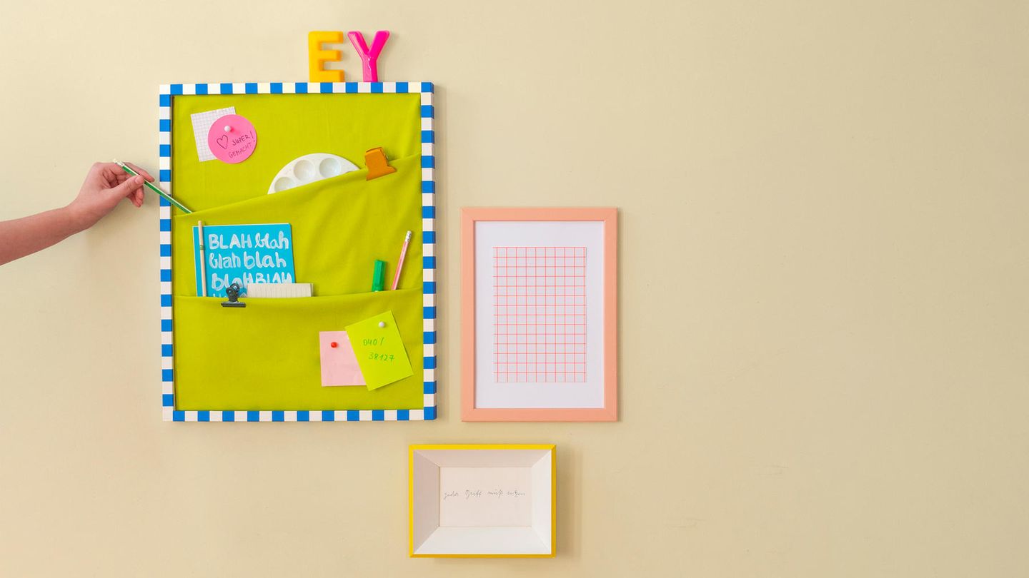 Pinnwand selber machen – An einer Wand hängt eine Pinnwand mit Taschen, darin sind unter anderem Stifte und eine Mischpalette