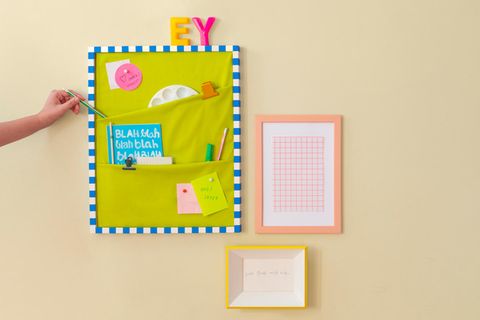 Pinnwand selber machen – An einer Wand hängt eine Pinnwand mit Taschen, darin sind unter anderem Stifte und eine Mischpalette