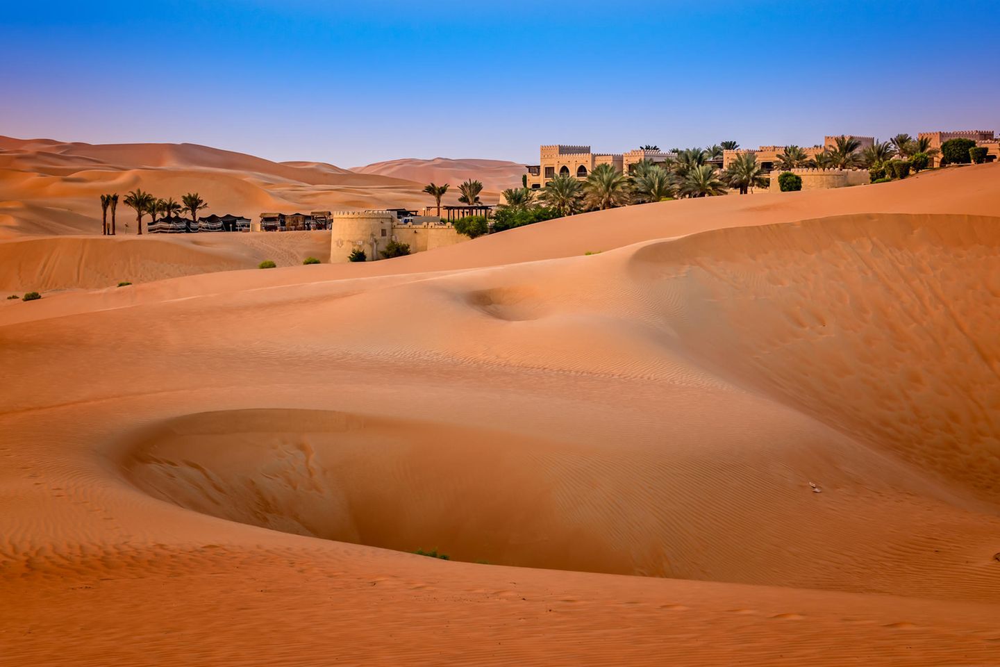 Pssst – Abu Dhabi's Dünen Palmen und Gebäude inmitten von Dünen