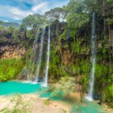 Wasserfall mit vielen grünen Pflanzen und blauem Wasser