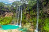 Wasserfall mit vielen grünen Pflanzen und blauem Wasser