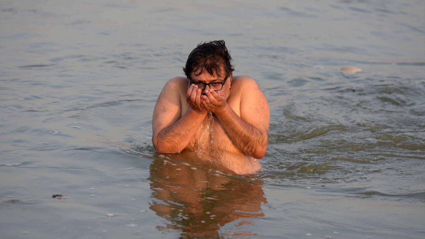 Ein Mann trinkt Wasser aus dem Fluss Ganga in Indien