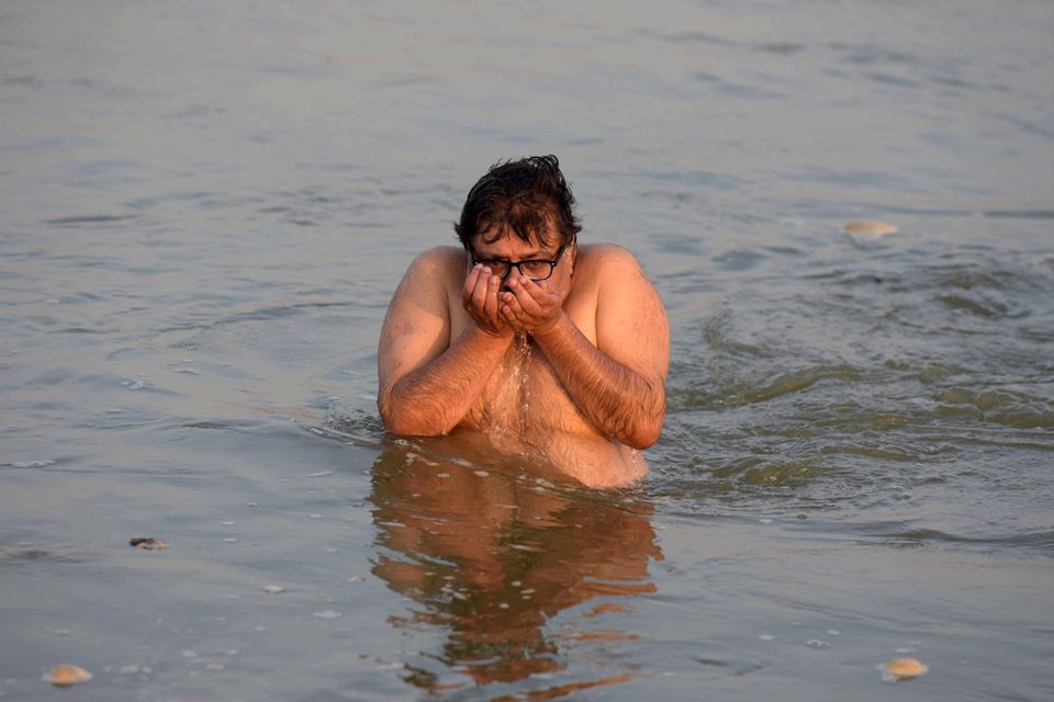 Ein Mann trinkt Wasser aus dem Fluss Ganga in Indien