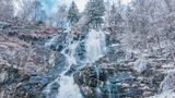 Wasserfall mit schneebedeckten Bäumen