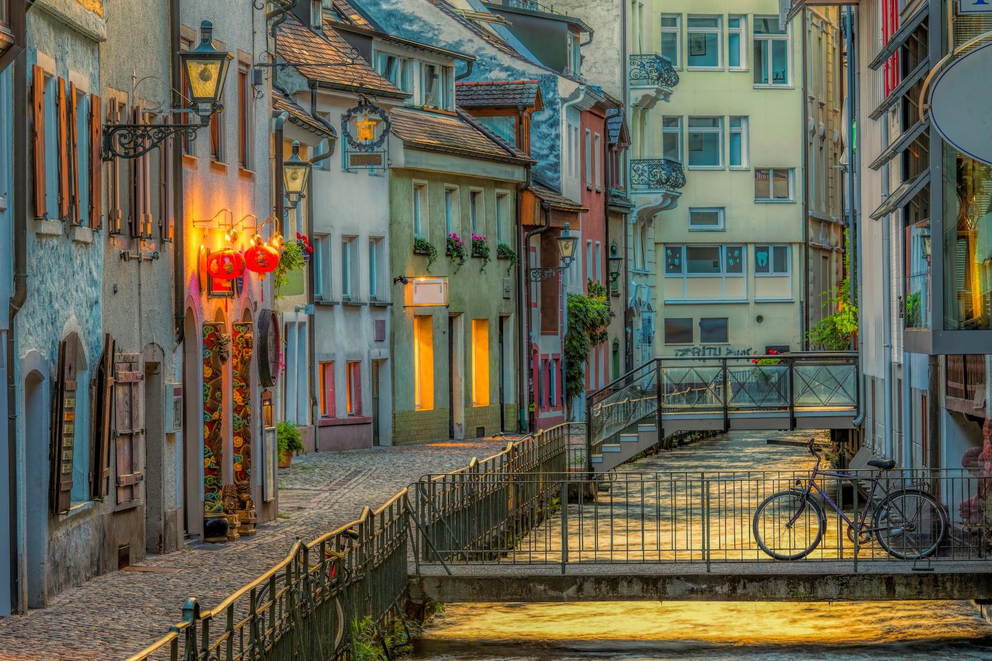 Beleuchtete Gasse mit bunten Häuschen an einem Bach in Freiburg