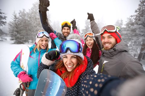 Frauen und Männer im Schnee mit Skibrillen auf dem Kopf