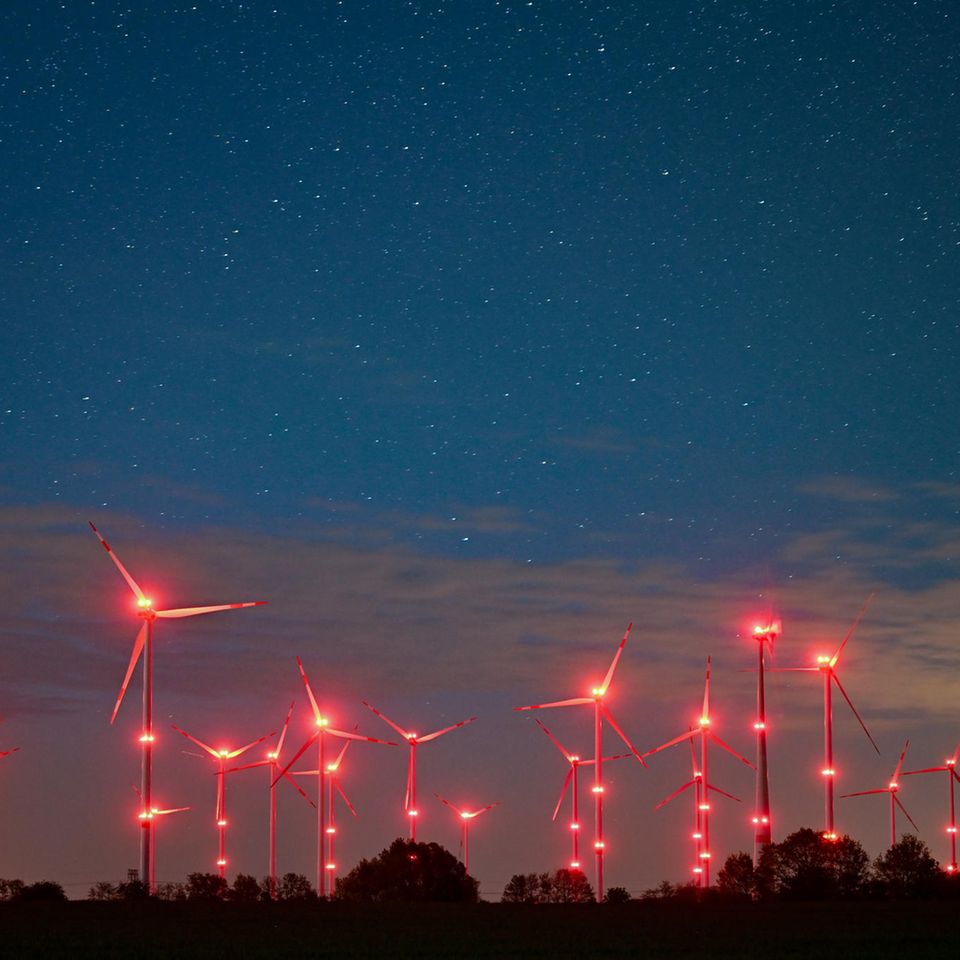 Brandenburg, Jacobsdorf: Die roten Positionslichter an Windenergieanlagen erhellen den Nachthimmel und die Landschaft