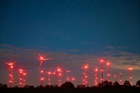Brandenburg, Jacobsdorf: Die roten Positionslichter an Windenergieanlagen erhellen den Nachthimmel und die Landschaft