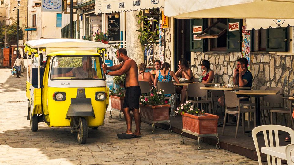 Ein Blick auf eine italienische Pizzeria, in der die Menschen draußen sitzen Ein Blick auf eine italienische Pizzeria, in der die Menschen draußen sitzen