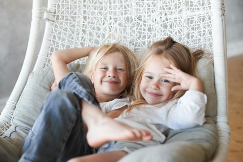 Zwei Schwestern kuscheln im Sessel
