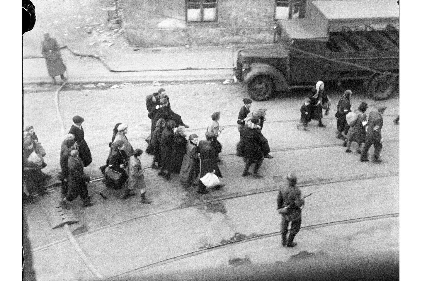 NEGATYW13100 – Jews being led to Umschlagplatz; photo taken from a window of St Zofia Hospital at the corner of Żelazna and Nowolipie Streets, most likely (to be confirmed) overlooking Nowolipie Street; author’s comment noted after the war at the back of the print held in the USHMM archive in Washington, DC:  ”Scenes from the evacuation of the ghetto, ca 20 April 1943”