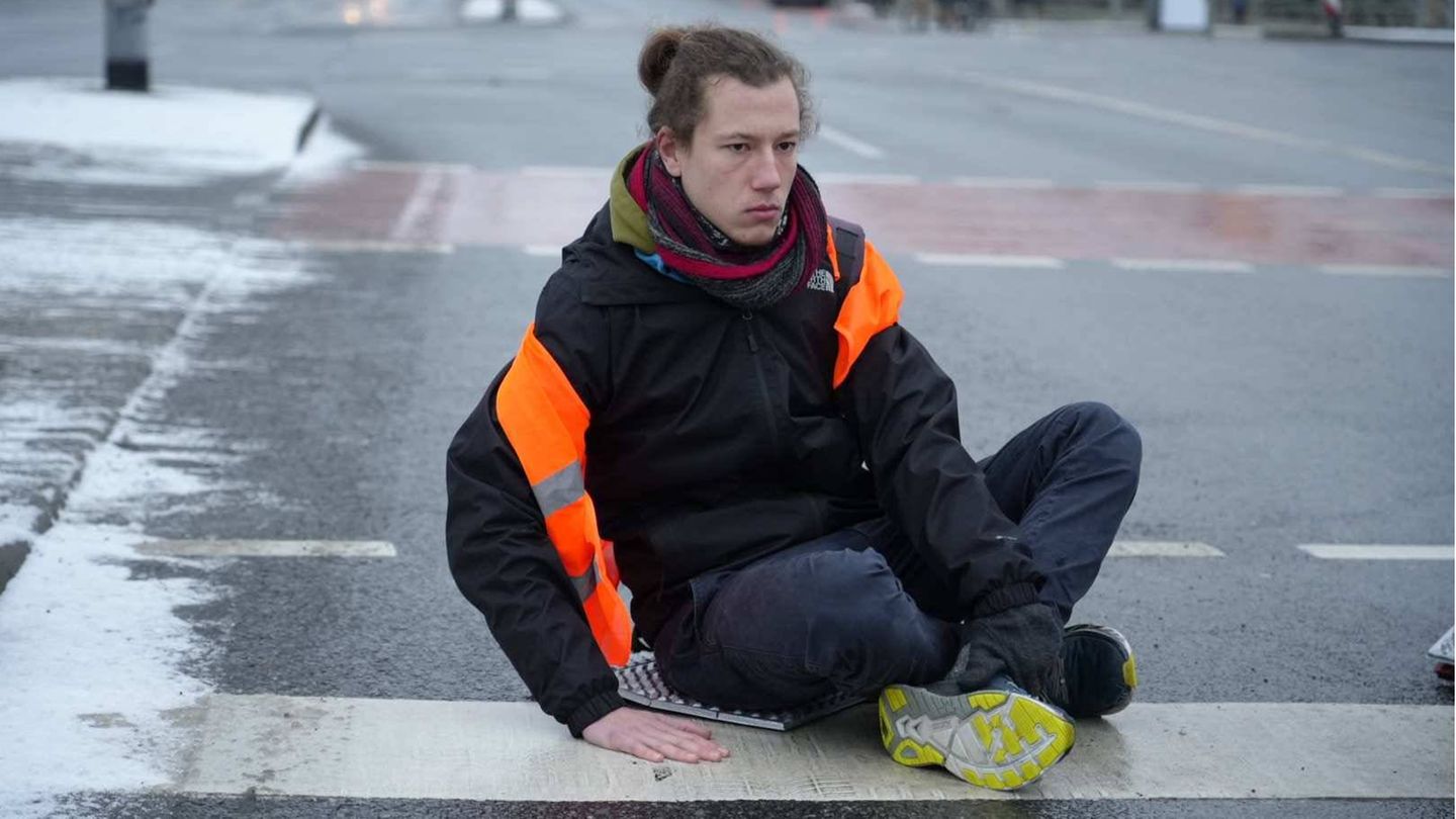Ein Klimaaktivist der letzten Generation sitzt auf der Straße und schaut traurig