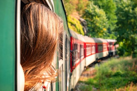 Frau reist mit dem Zug und schaut aus dem Fenster
