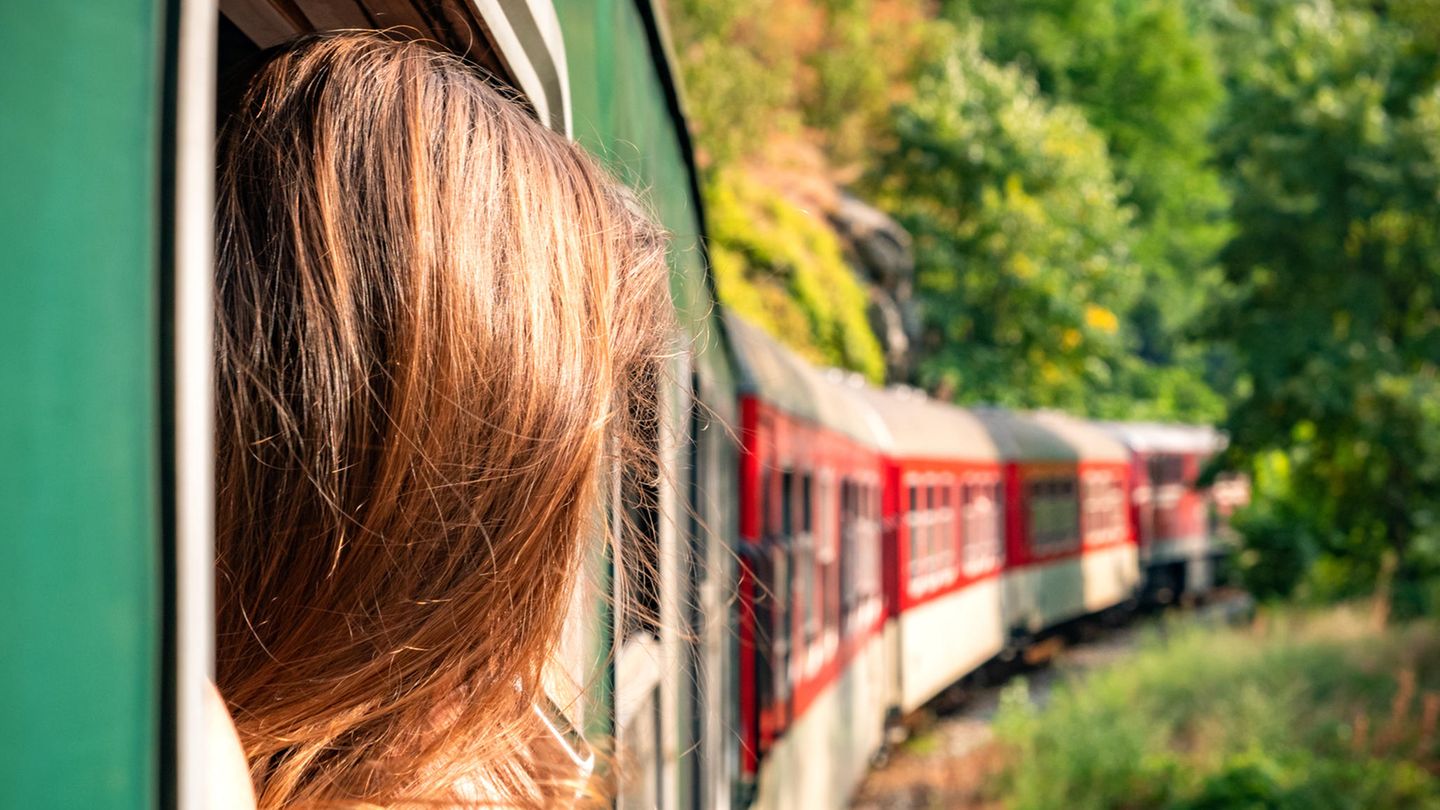 Frau reist mit dem Zug und schaut aus dem Fenster