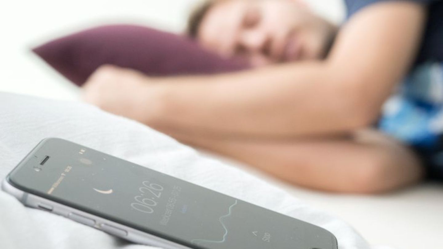 Ein Mann schläft, neben ihm liegt ein Handy, das den Schlaf überwacht