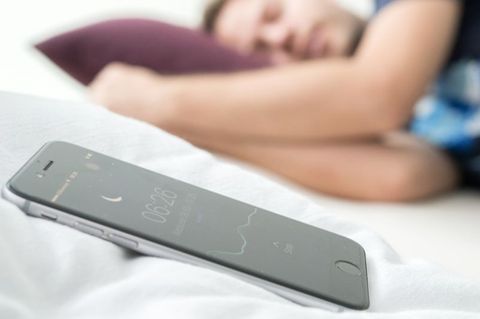 Ein Mann schläft, neben ihm liegt ein Handy, das den Schlaf überwacht