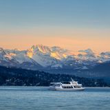Kleines Schiff auf dem Zürichsee, im Hintergrund sind die Alpen zu sehen