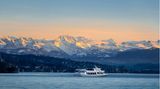 Kleines Schiff auf dem Zürichsee, im Hintergrund sind die Alpen zu sehen