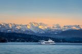 Kleines Schiff auf dem Zürichsee, im Hintergrund sind die Alpen zu sehen