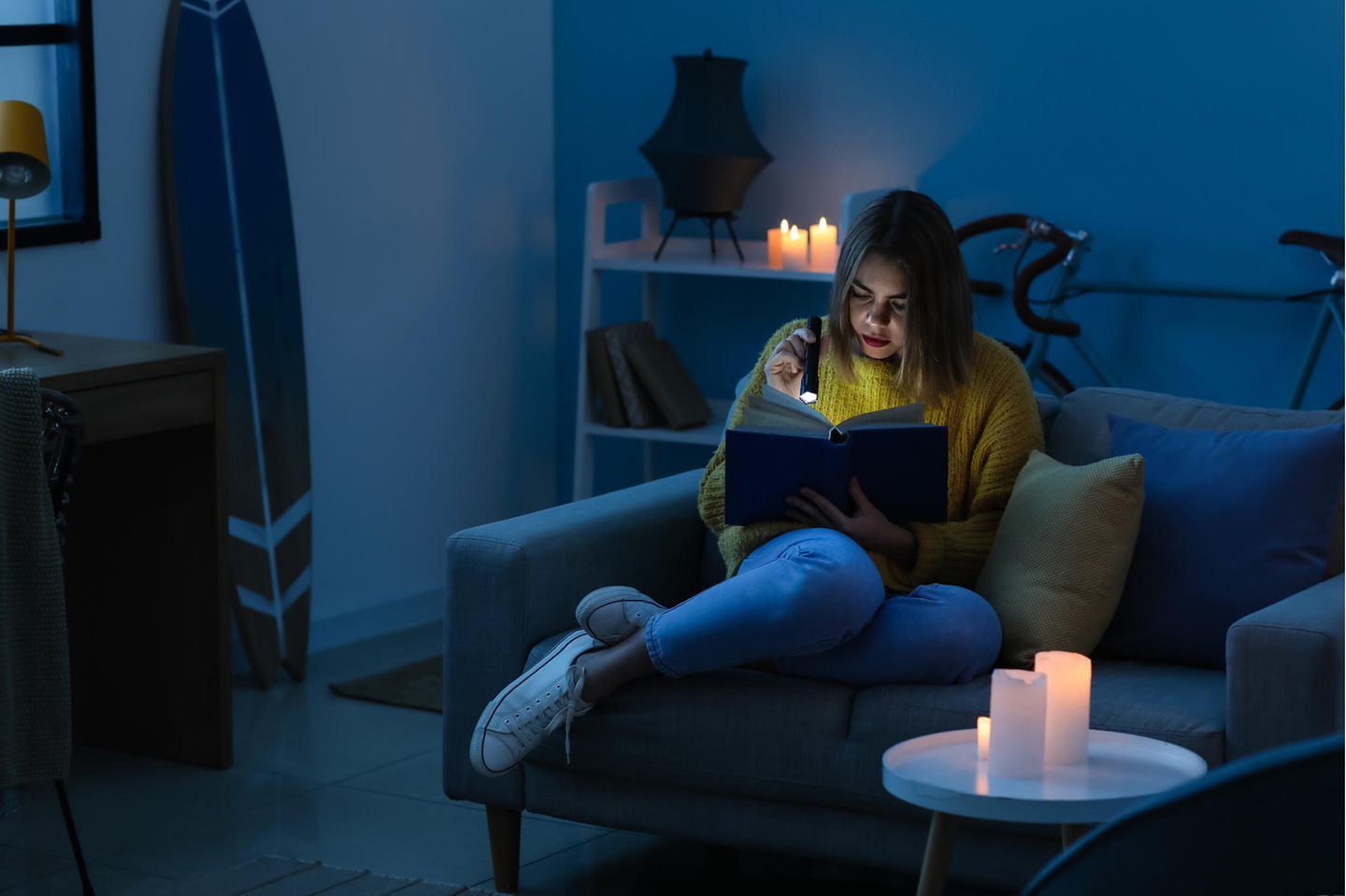 Junge Frau liest ein Buch mit Taschenlampe