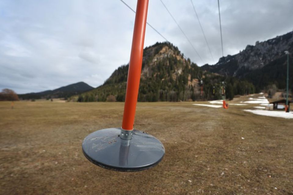 Hier läuft nichts: Teller eines Schleppliftes baumeln an einer Skipiste im bayerischen Schwangau, auf der noch Reste von Kunstschnee zu sehen sind