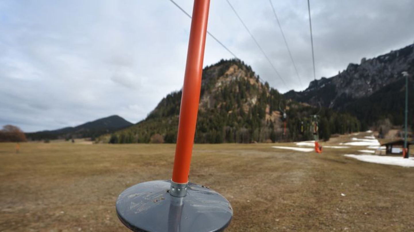 Hier läuft nichts: Teller eines Schleppliftes baumeln an einer Skipiste im bayerischen Schwangau, auf der noch Reste von Kunstschnee zu sehen sind
