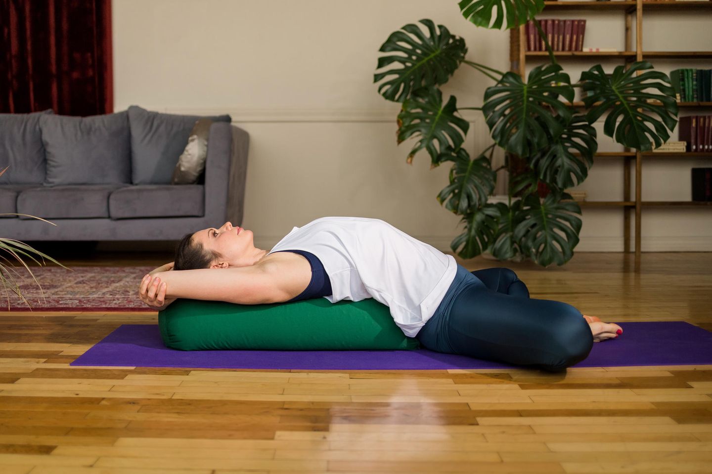 Eine junge Frau nutzt ein Yoga Bolster als Zubehör für ihre Yoga Praxis.