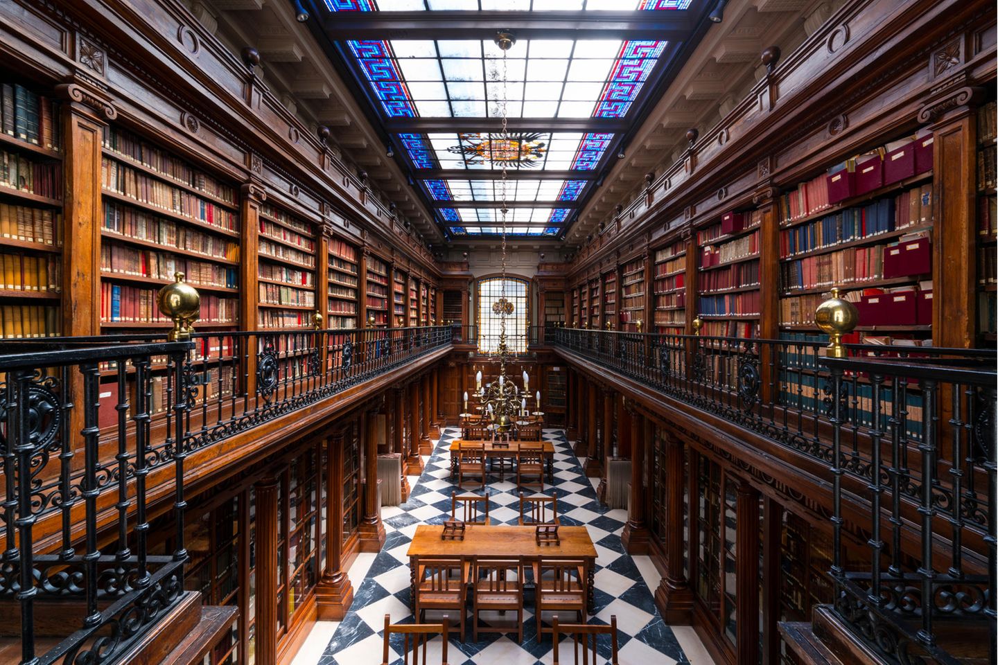 Paradies für Wissensdurstige Bibliothek mit viel Holz und bunter Glasdecke
