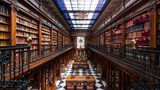 Bibliothek mit viel Holz und bunter Glasdecke