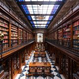 Bibliothek mit viel Holz und bunter Glasdecke