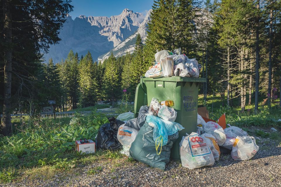Ein überfüllter Abfalleimer in schönes Landschaft in den Alpen