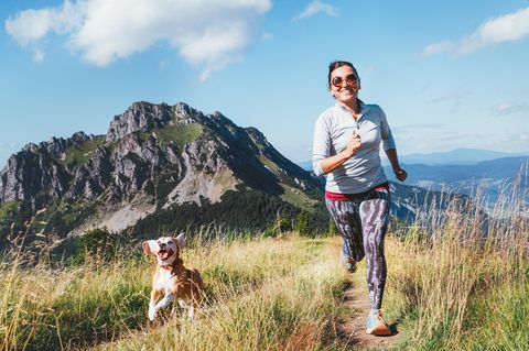 Joggen mit Hund: Lächelnde Frau läuft mit Ihrem Hund