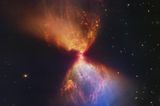 Der hier farbig dargestellte Dunkelnebel L1527 im Sternbild Stier erinnert an eine Sanduhr. In der Mitte befindet sich ein gerade mal rund 100 000 Jahre alter Protostern. Er zieht immer mehr Materie an, bis irgendwann in seinem Inneren die Kernfusion zündet und er selbst Energie freisetzt