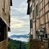 Blick zwischen zwei Fachwerkhäusern auf den nebelverhangenen Dschungel