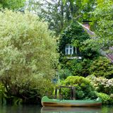 Efeubewachsenes Haus von viel Grün umgeben und einem kleinen Boot davor