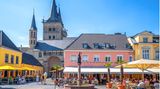 Bunte Hausfassaden an einem Platz mit einem Brunnen und einer Kirche